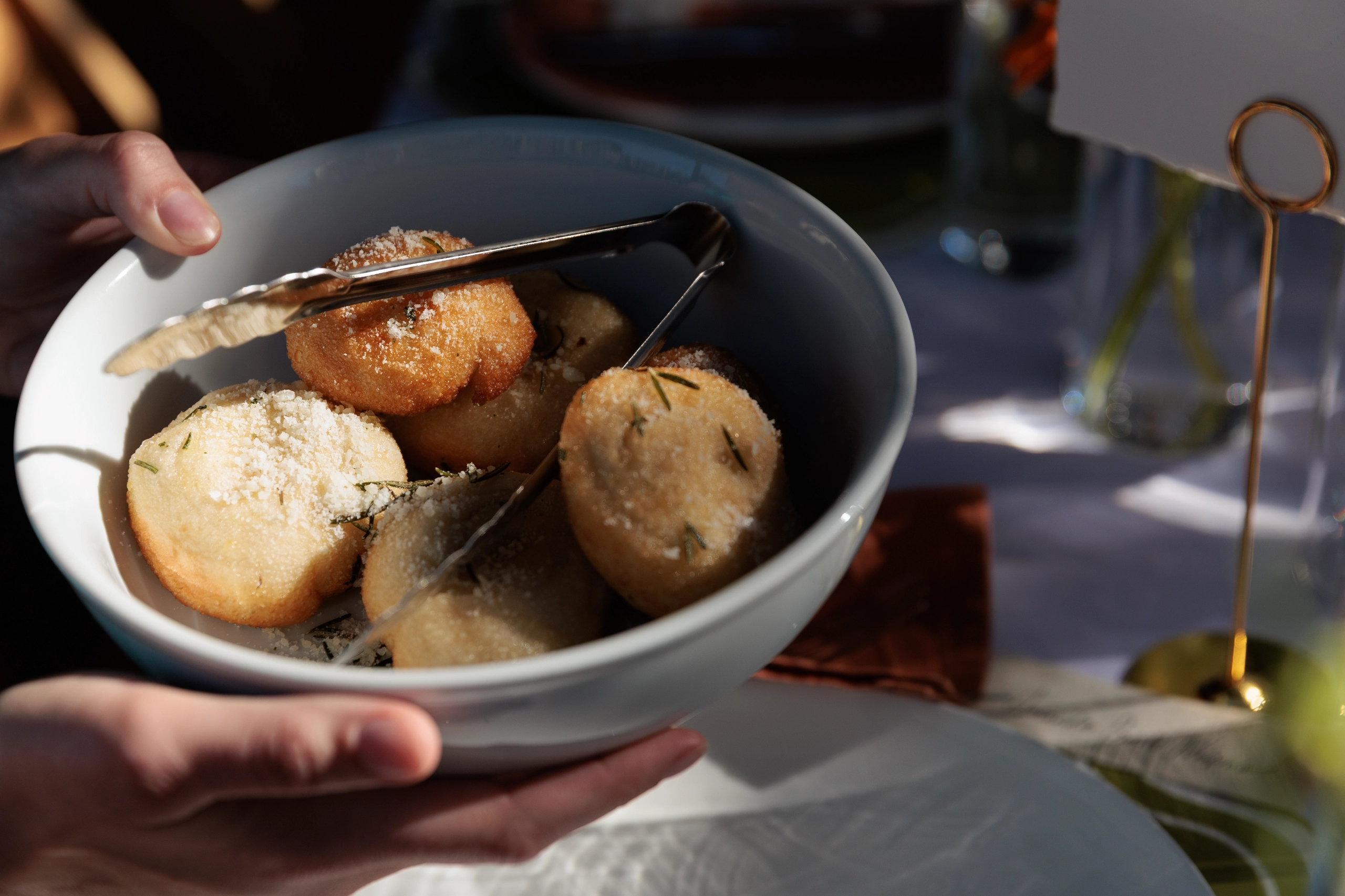 White bowl with cheese and rosemary bread rolls.