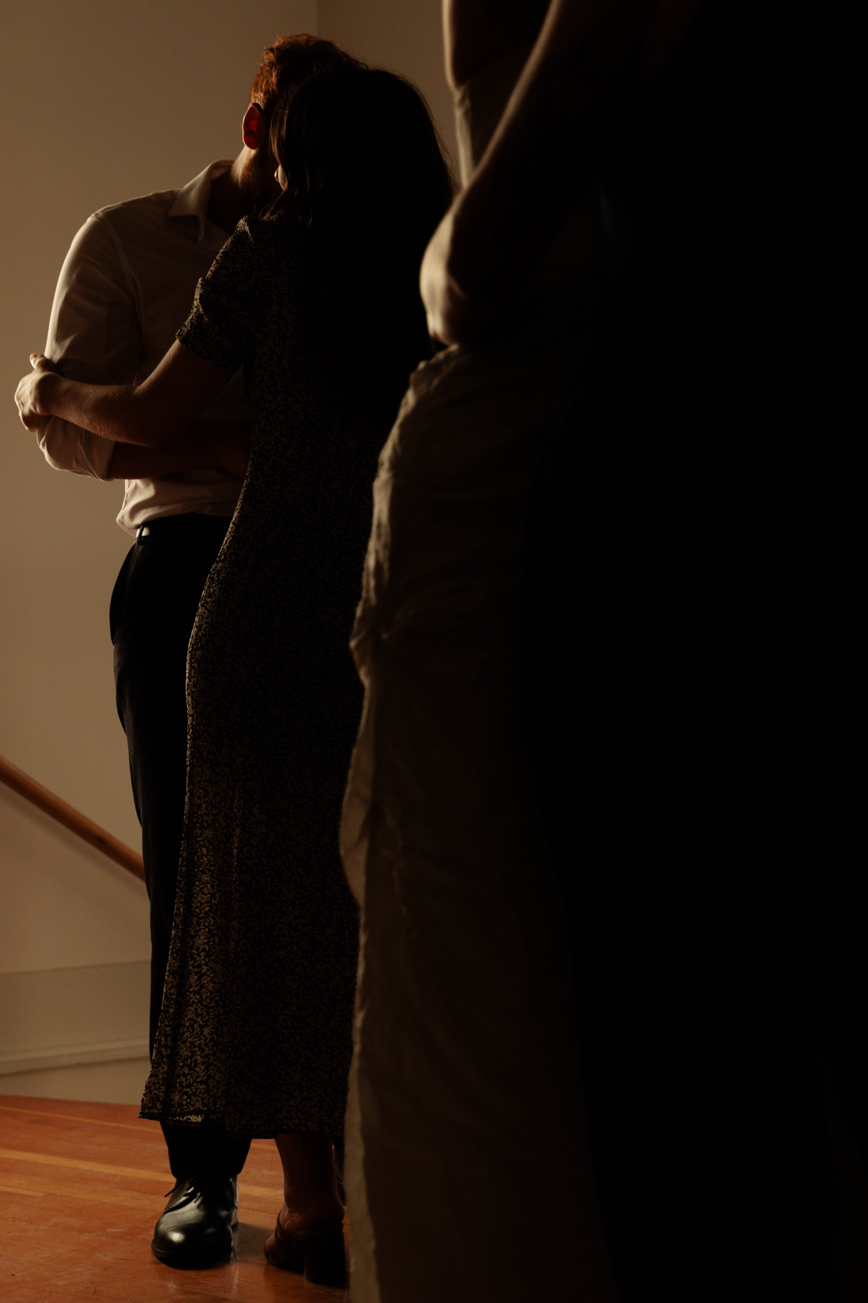 Wedding guests slow dance, illuminated by golden window light.
